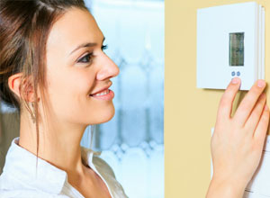 Woman adjusting wall thermostat