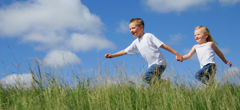 Boy and girl running in grassy field