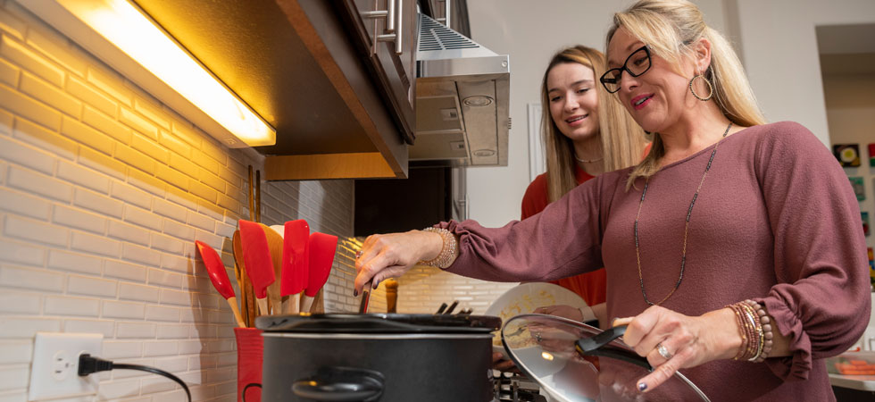 Mom and daughter in the kitchen stirring pot