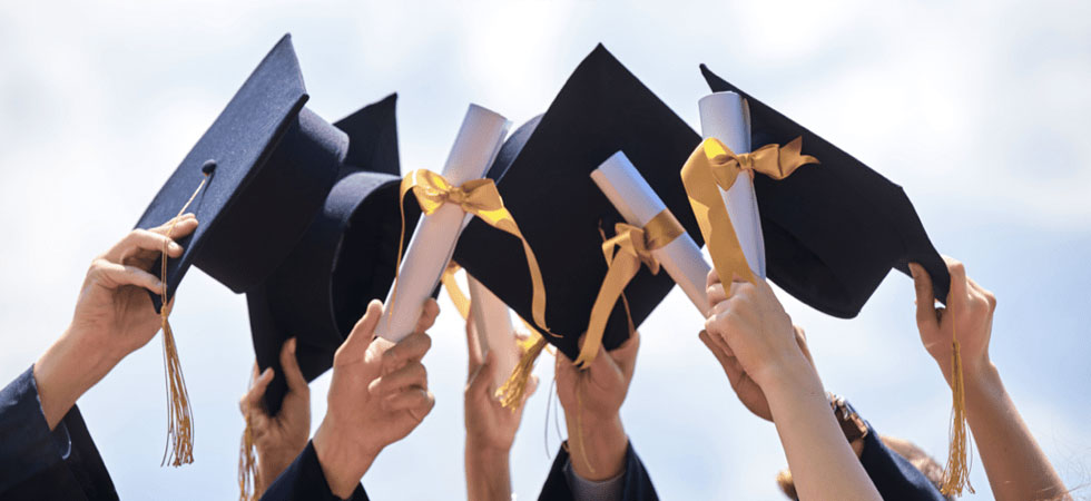 A group holding graduation caps and diplomas in the air