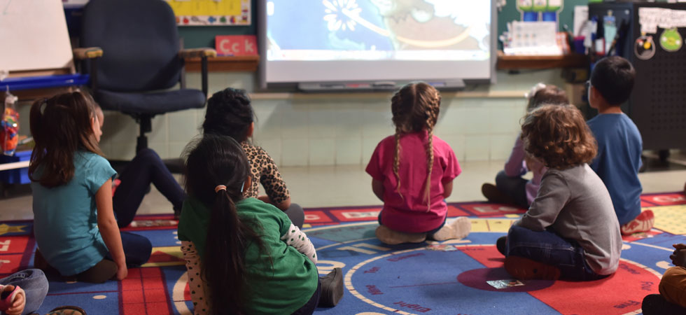 Kids in a class room watching a video