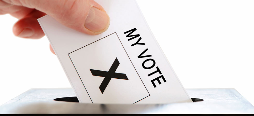 Close-up of hand putting ballot in a ballot box