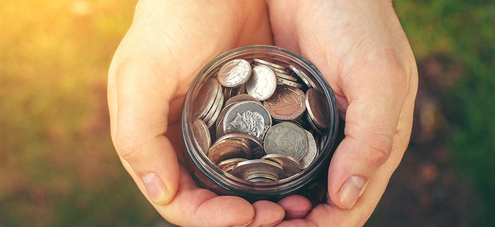 Pair of hands cupping a glass jar full of coins