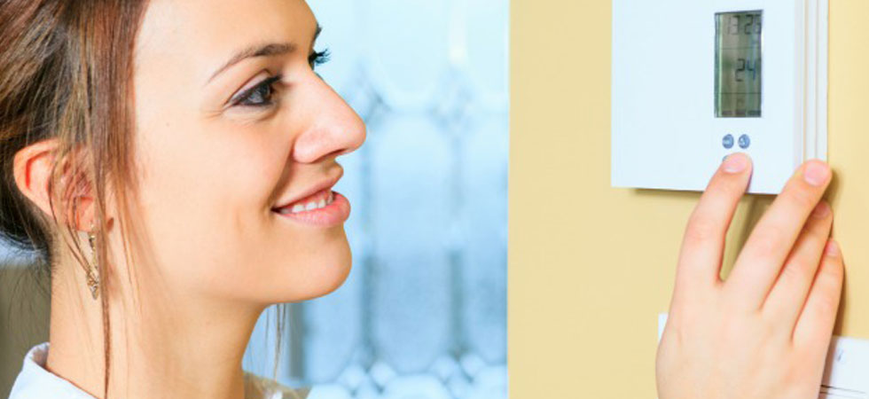 Woman adjusting wall thermostat