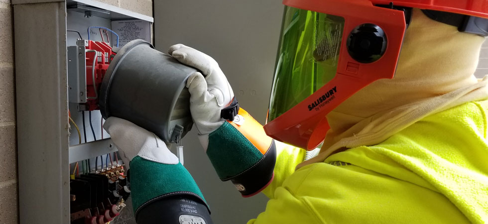 Worker in personal protective equipment performing maintenance on an electric meter