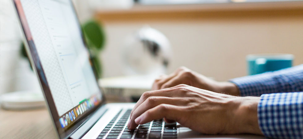 Hands typing on a laptop