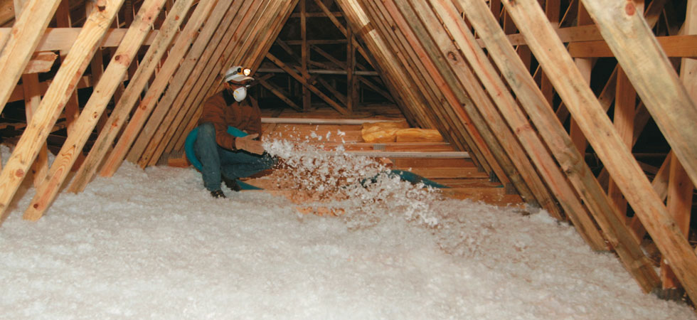 Man blowing in insulation in attic