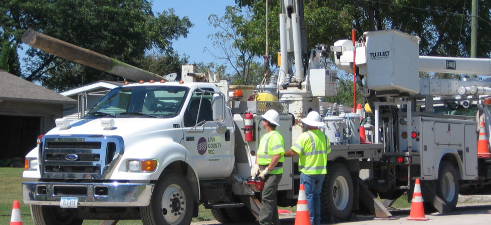 Electric service truck setting a new utility pole